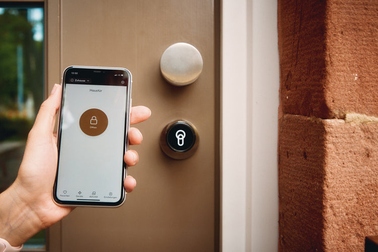 Ein Handy mit geöffneter keyota App wird vor einer Tür mit installiertem keyota Smart Lock gehalten, bereit, die Tür mit der App zu öffnen