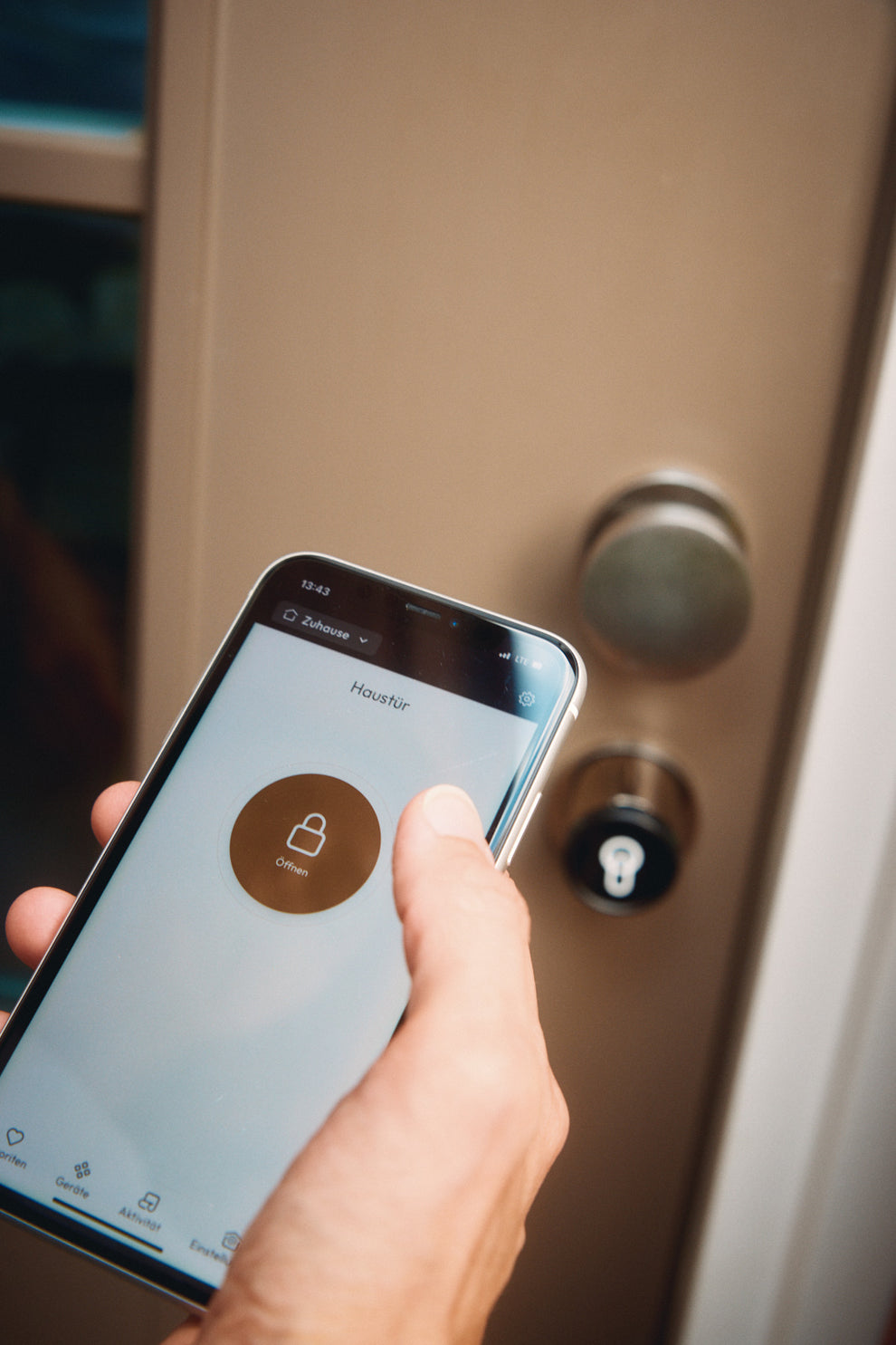 Ein Handy mit geöffneter keyota App wird vor einer Tür mit installiertem keyota Smart Lock gehalten, bereit, die Tür mit der App zu öffnen