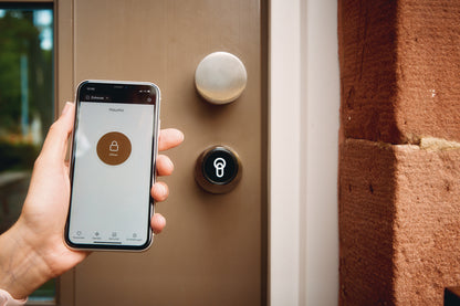 Ein Handy mit geöffneter keyota App wird vor einer Tür mit installiertem keyota Smart Lock gehalten, bereit, die Tür mit der App zu öffnen.