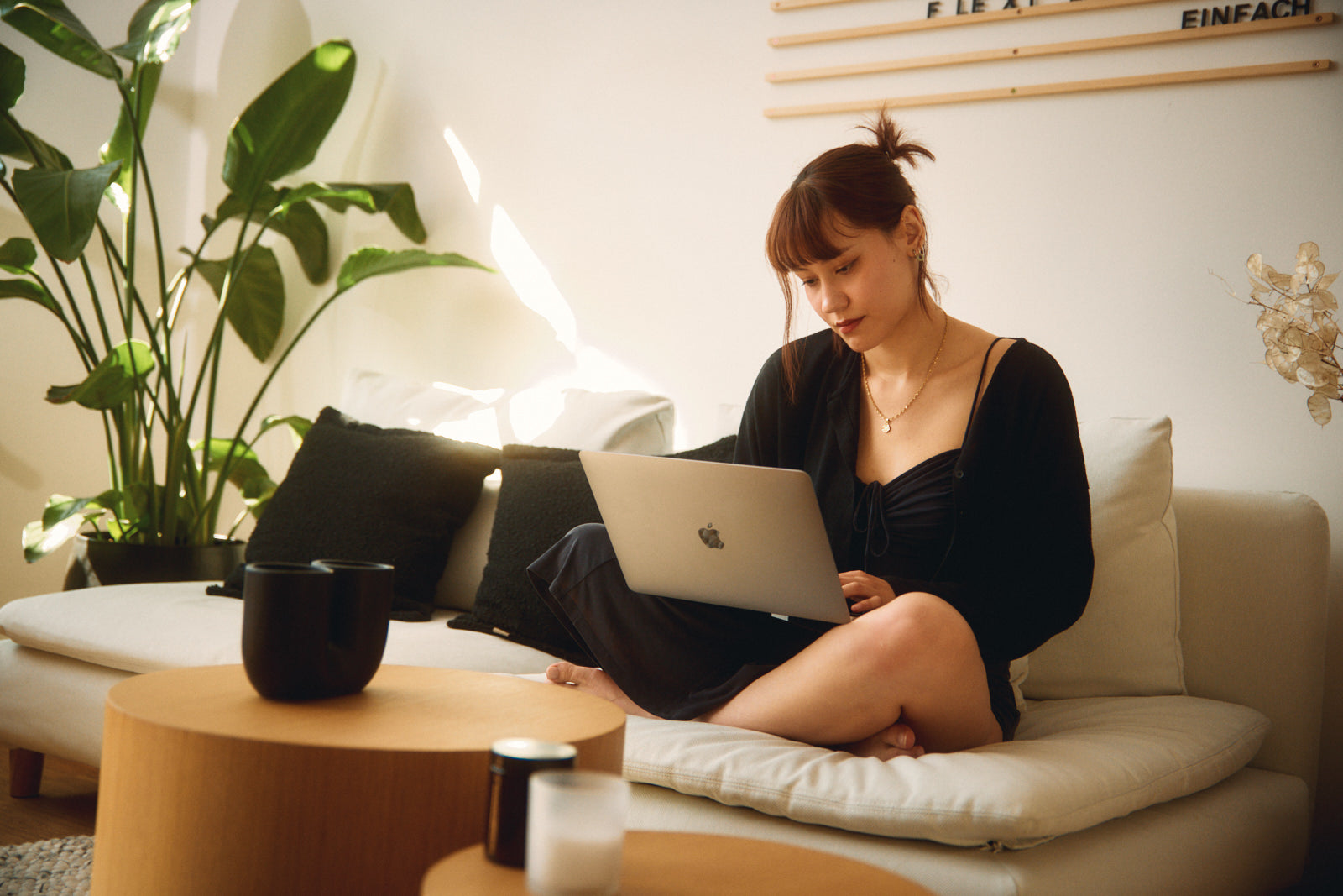 Eine Frau sitzt auf der Couch mit einem Laptop auf ihrem Schoß.
